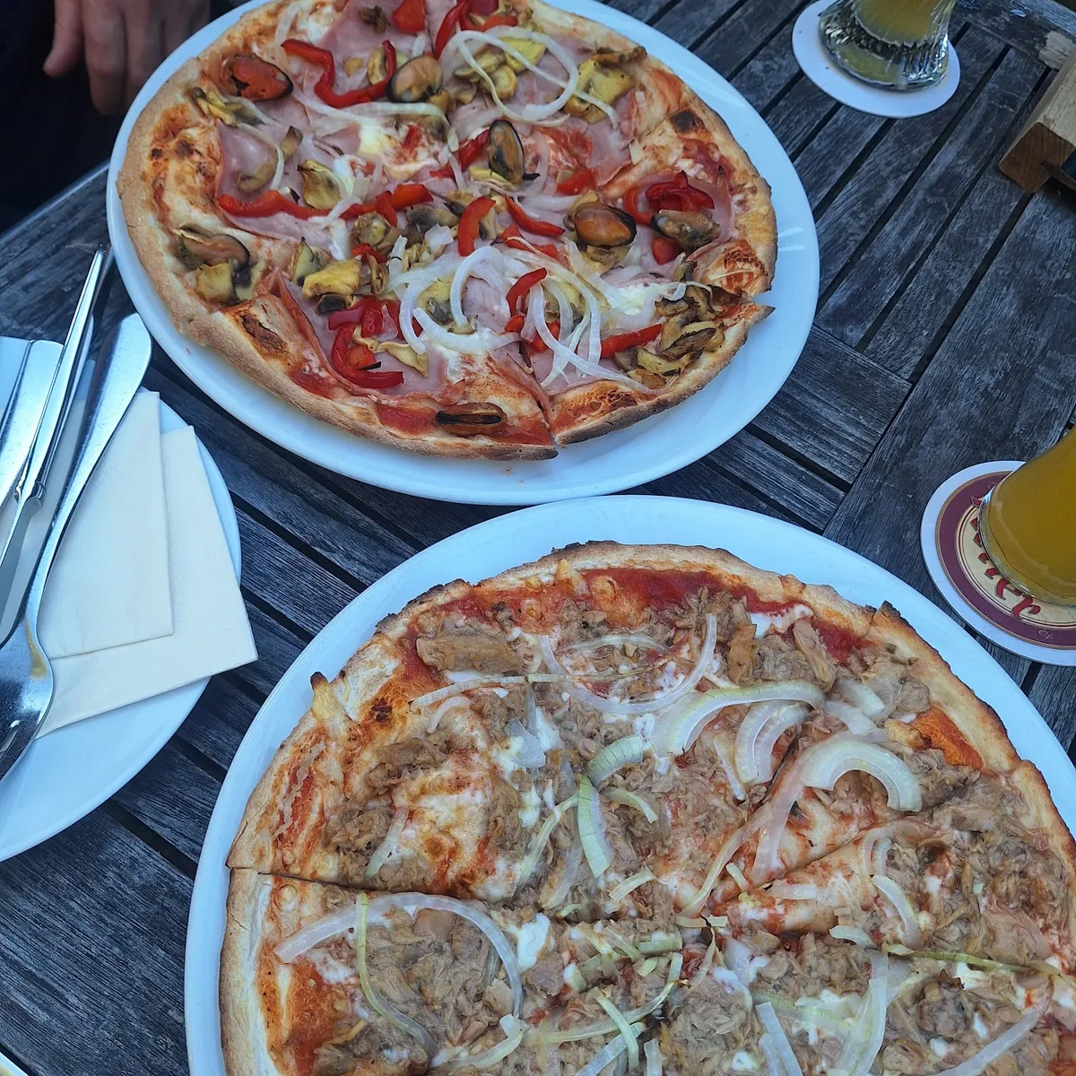 Zwei Pizzen auf einem Holztisch im Biergarten